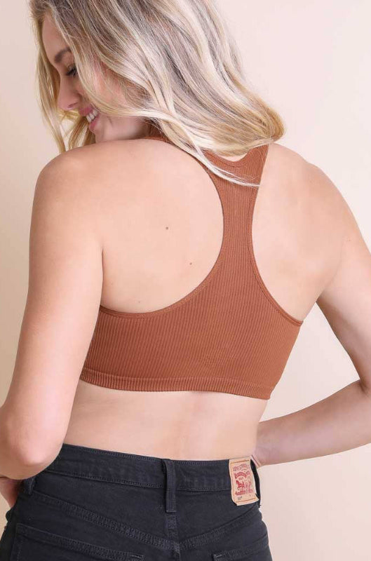 Woman wearing a brown ribbed crop top against a beige background