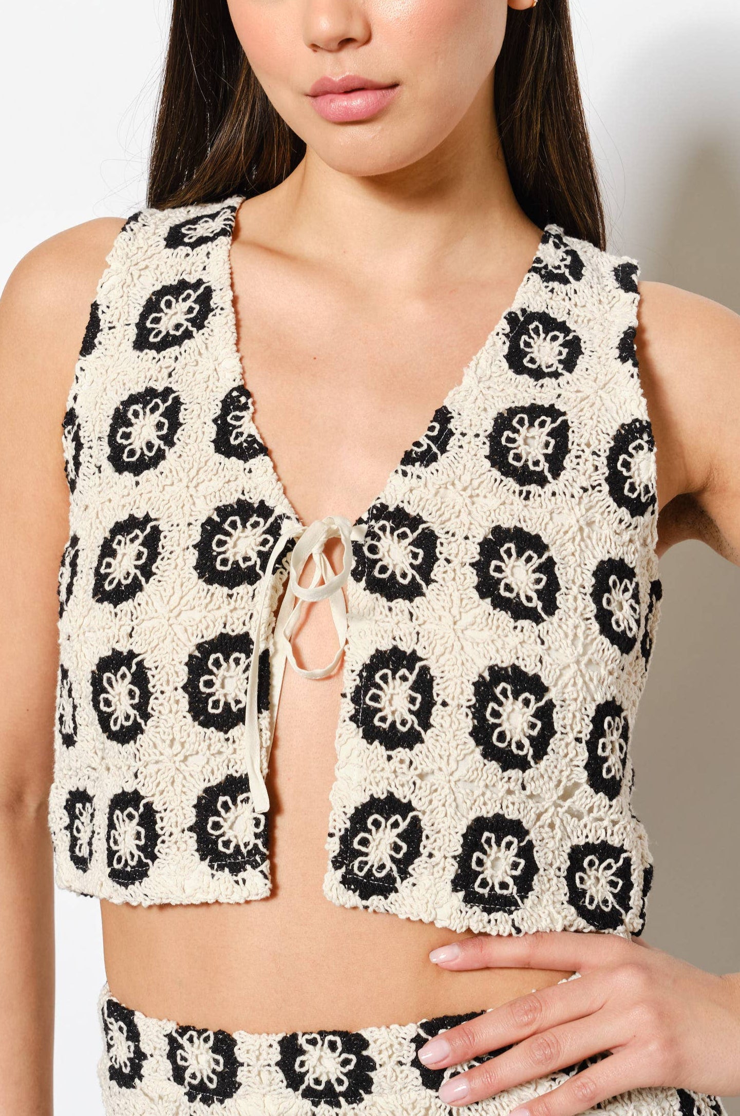 Woman wearing a black and ecru patterned outfit against a plain background