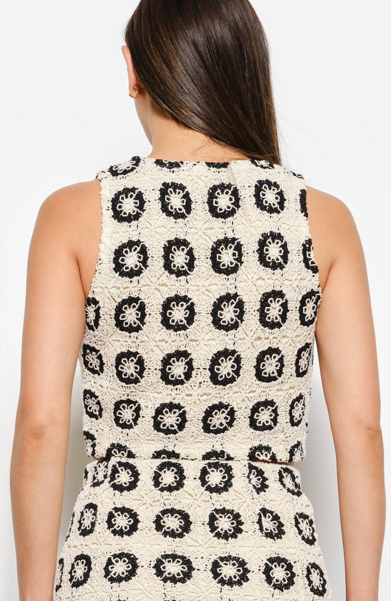 Woman wearing a sleeveless top with a black and white pattern against a white background