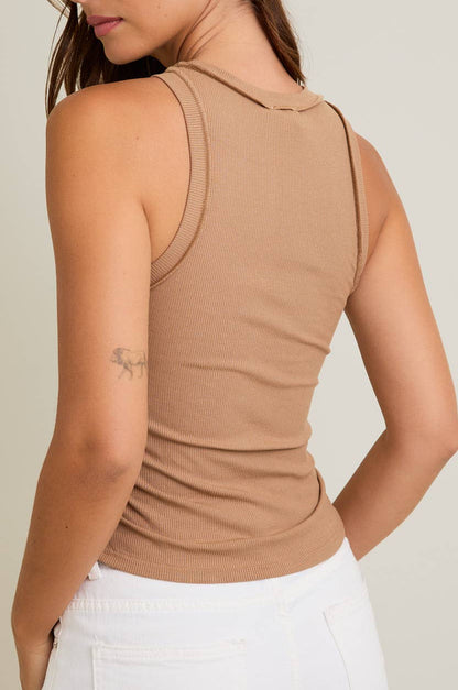 Woman wearing a beige sleeveless top against a plain background