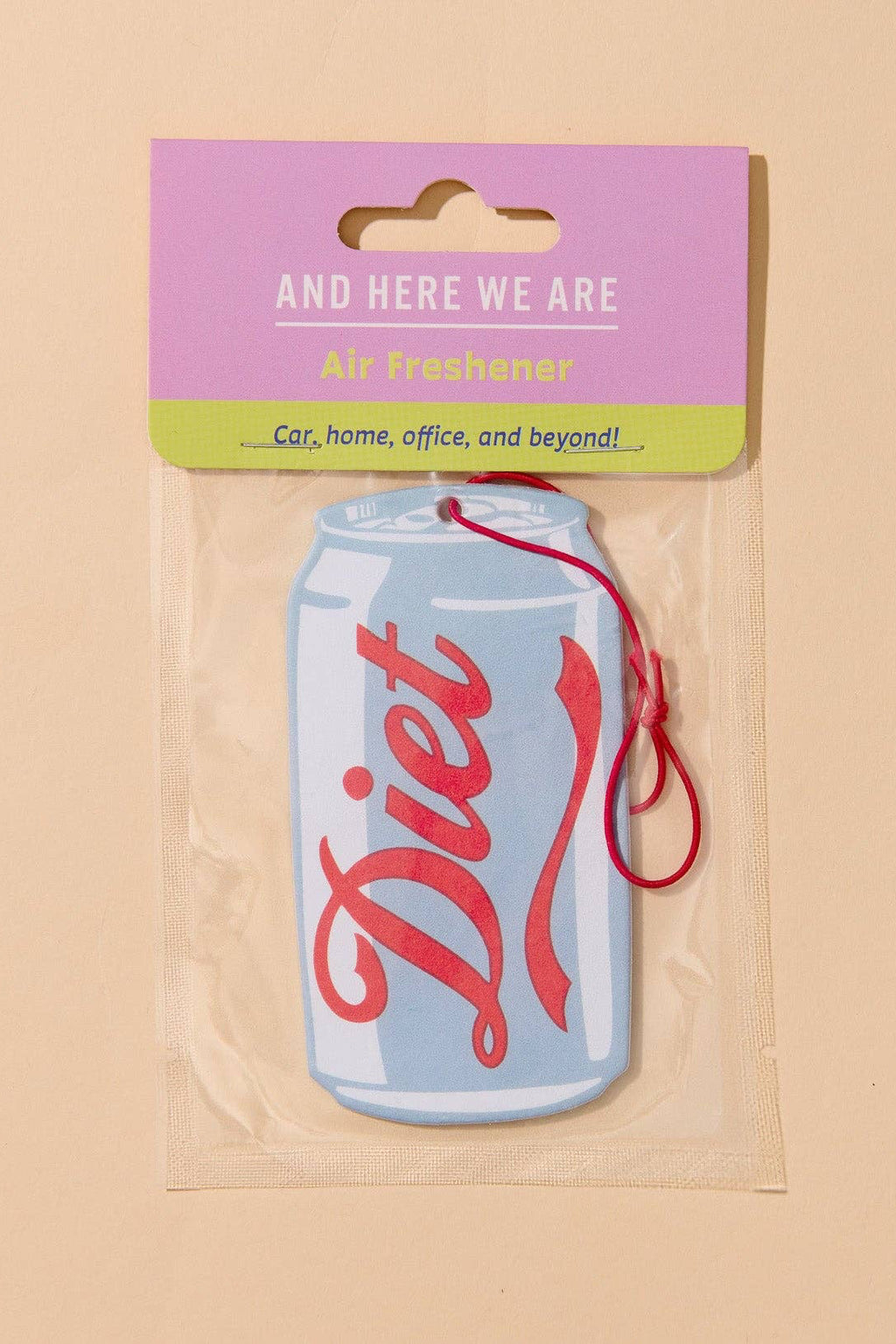 A Diet air freshener car fragrance shaped like a light blue soda can with red script lettering, sealed in a clear plastic bag with a pink and green header card that reads 'AND HERE WE ARE Diet freshener'.