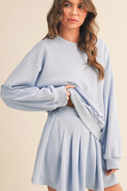 Woman wearing a light blue sweater and skirt set on a beige background