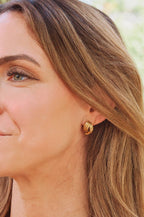 Woman wearing gold hoop earrings with a blurred natural background