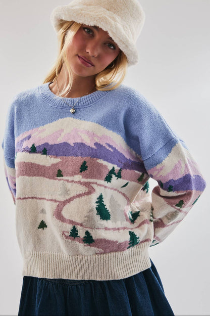 Person wearing a sweater with a mountain landscape design on a plain background