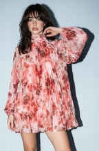 Woman wearing a floral dress against a plain background