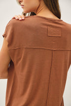 Brown t-shirt with a patch on a plain background