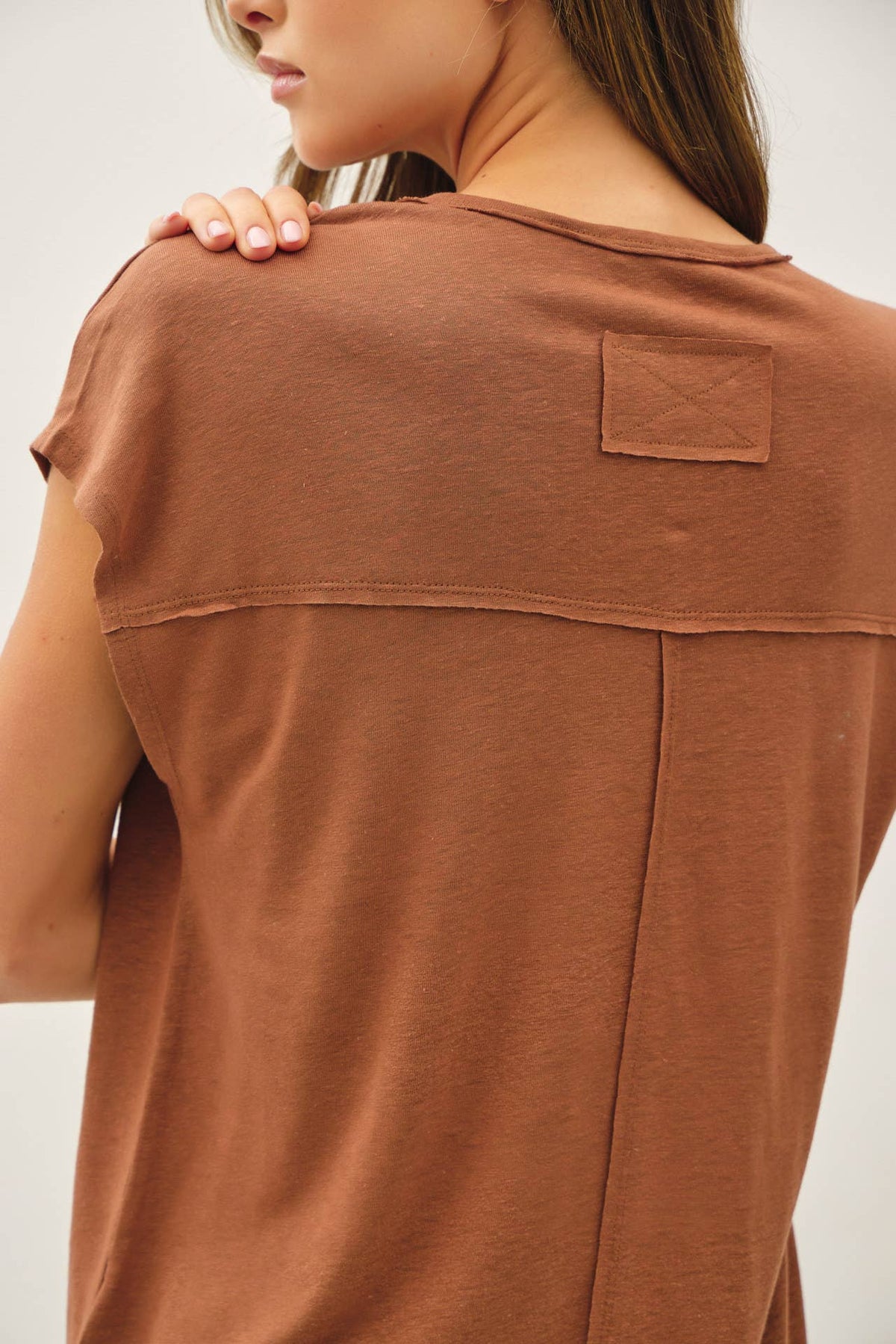 Brown t-shirt with a patch on a plain background