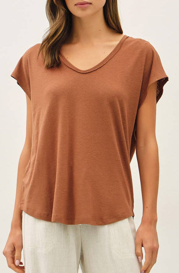 Woman wearing a brown top and white pants on a white background