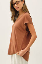 Woman wearing a brown top and white pants on a white background