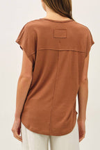 Woman wearing a brown top and white pants on a white background