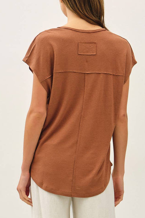 Woman wearing a brown top and white pants on a white background