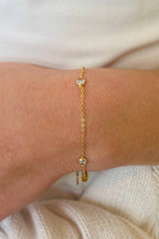 Gold bracelet with cubic zirconia on a wrist against a white background
