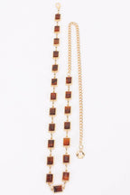 Gold chain with brown square beads on a white background