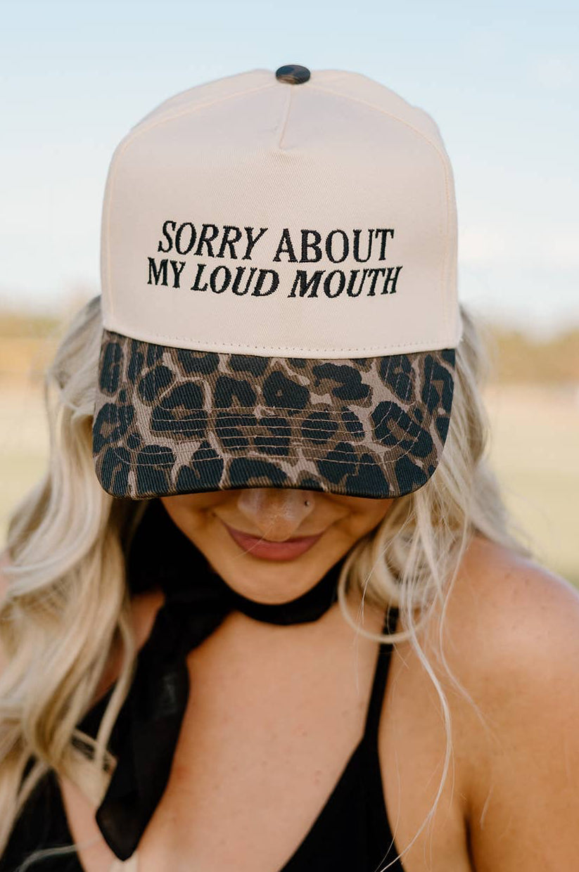 Person wearing a cap with 'Sorry About My Loud Mouth' text and leopard print bill.