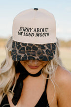 Person wearing a cap with 'Sorry About My Loud Mouth' text and leopard print bill.