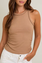 Woman wearing a nude tank top against a beige background