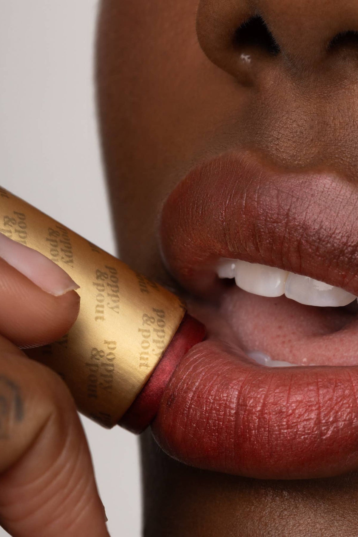 Close-up of a person applying lipstick with a gold tube.