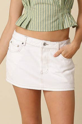 Person wearing a green and white striped top and white denim skirt on a beige background
