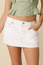 Person wearing a green and white striped top and white denim skirt on a beige background