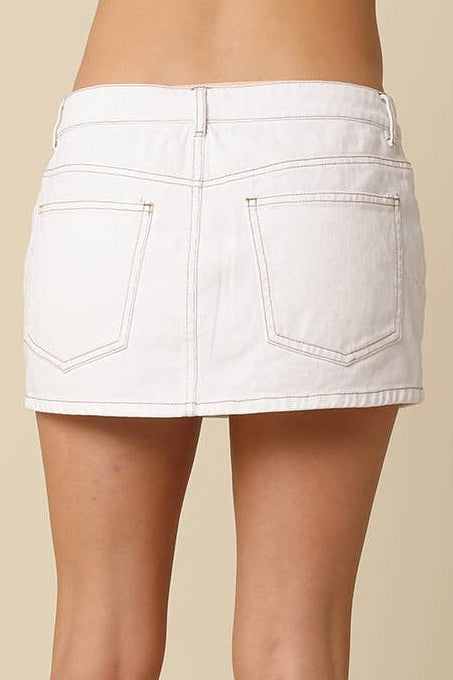 White denim skirt worn by a person on a beige background