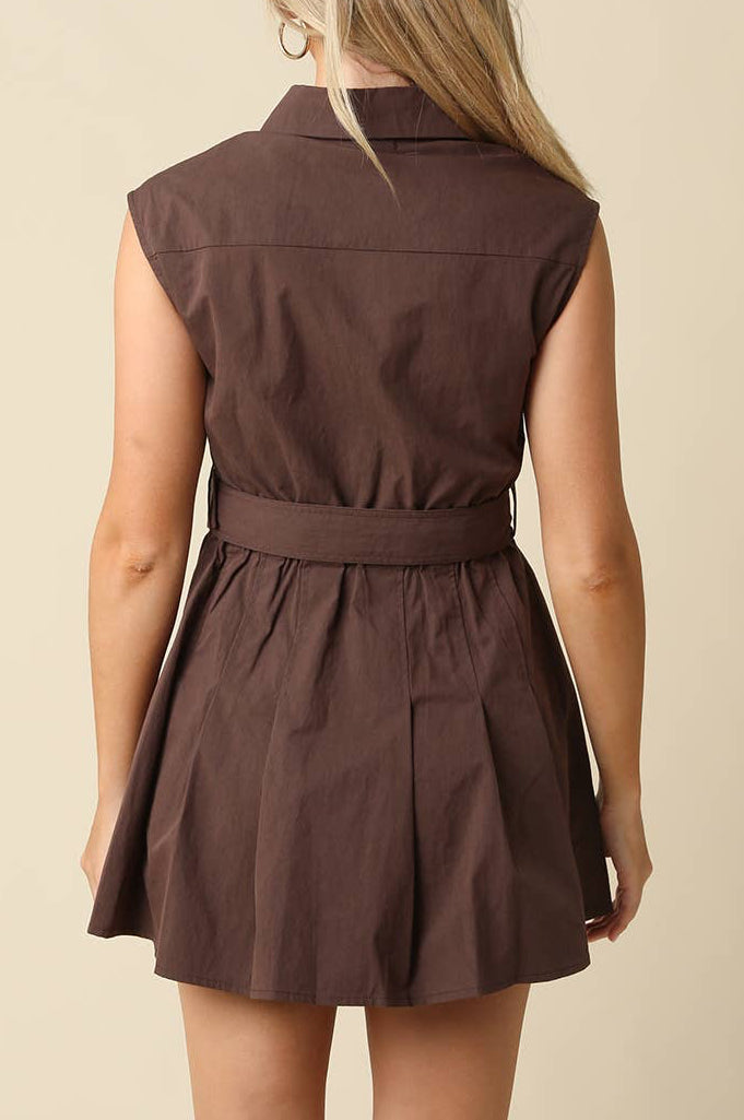 A woman shown from the back wearing a sleeveless brown mini dress with a collar and matching waist tie, set against a plain beige background.