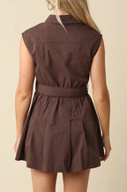 A woman shown from the back wearing a sleeveless brown mini dress with a collar and matching waist tie, set against a plain beige background.
