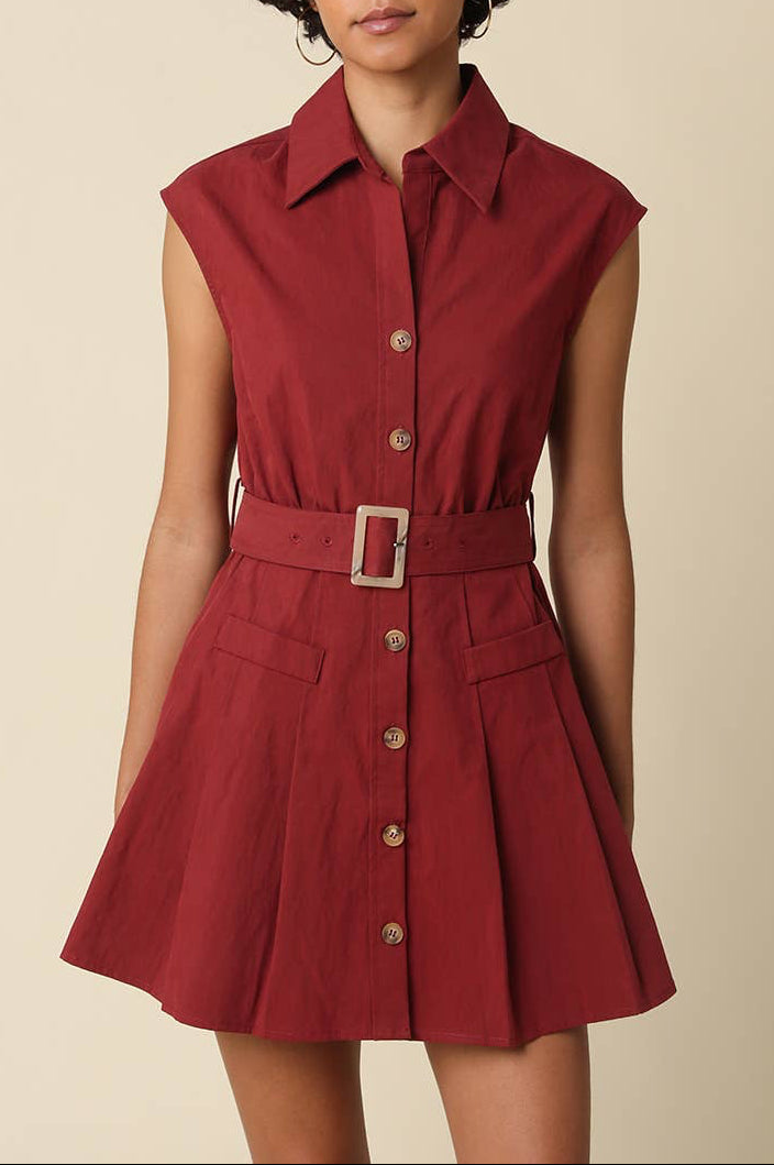 Woman wearing a red sleeveless dress with buttons on a beige background