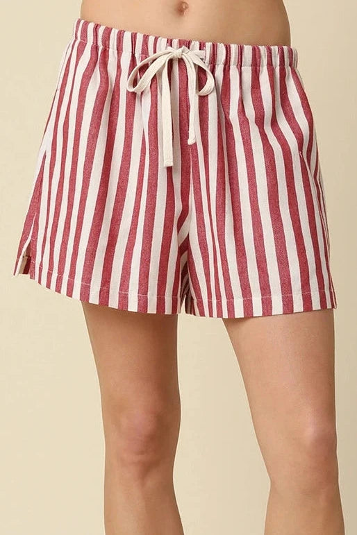 Red and white striped shorts worn by a person on a beige background