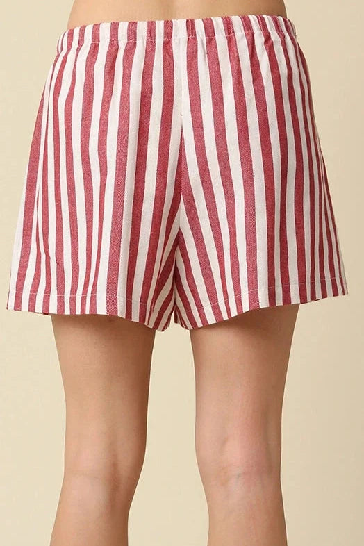 Red and white striped shorts worn by a person on a beige background