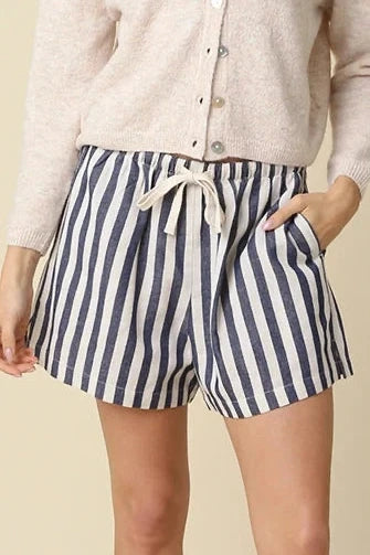 Woman wearing a white shirt and striped shorts on a beige background