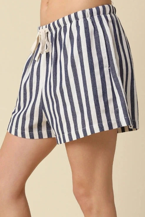 Person wearing navy and white striped shorts on a beige background