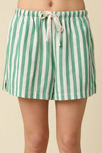 Green and white striped shorts worn by a person on a beige background