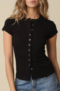 Woman wearing a black short-sleeve button-up shirt and blue jeans against a beige background