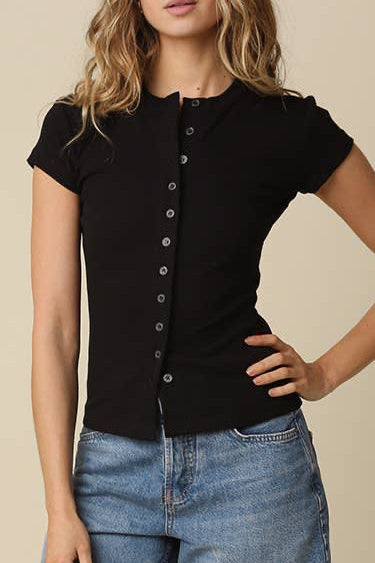 Woman wearing a black top and blue denim shorts against a beige background