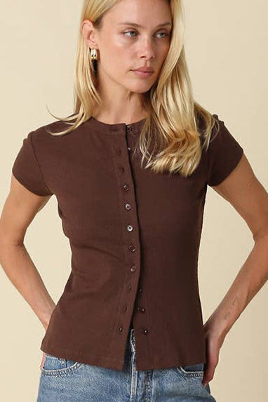 Woman wearing a brown top and blue shorts against a beige background