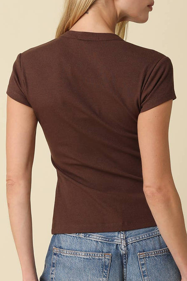 Woman wearing a brown t-shirt and blue jeans against a beige background