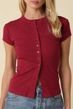Woman wearing a red button-up shirt and blue jeans against a beige background