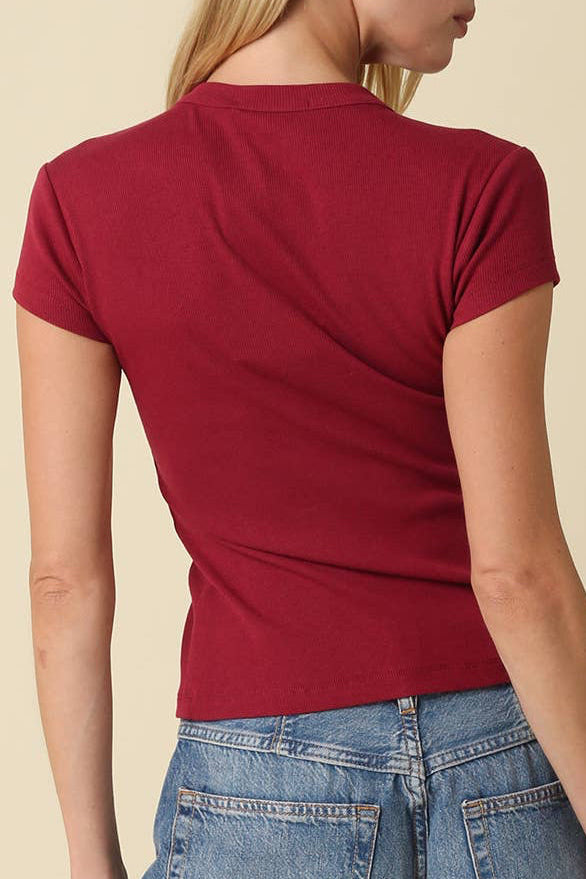 Woman wearing a red t-shirt and blue jeans against a beige background