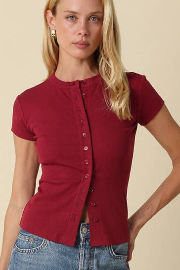 Woman wearing a red shirt and blue denim shorts on a beige background