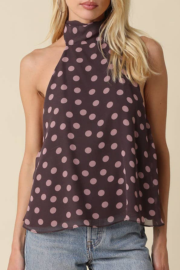 Woman wearing a polka dot top and jeans on a beige background