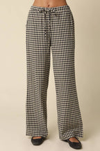Black and white gingham wide-leg pants with a drawstring waist, shown on a model from the waist down against a plain beige background.
