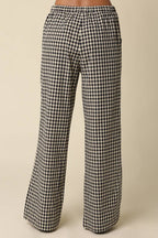 Black and white gingham wide-leg pants shown on a model from the back, against a solid beige background.