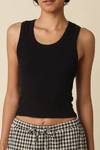 Woman wearing a black tank top and checkered pants against a beige background