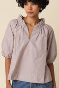 A woman wearing a short-sleeve puff-sleeve blouse with vertical pink and white stripes, paired with blue denim jeans, against a solid beige background.