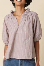 Woman wearing a striped shirt and denim skirt on a beige background