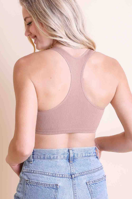 Woman wearing a ribbed crop top and blue jeans on a beige background