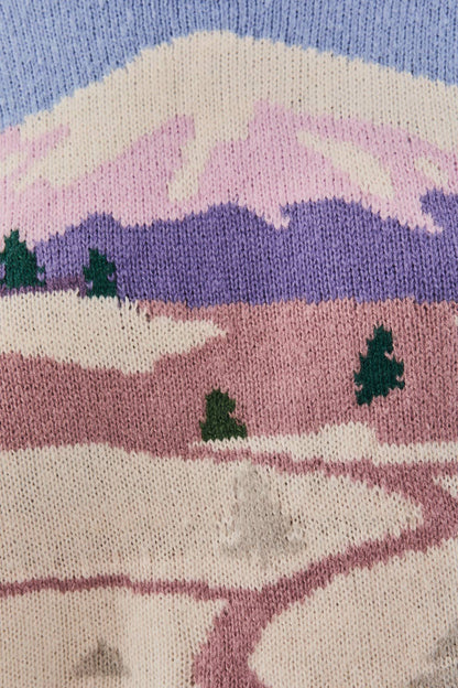 Knitted landscape with mountains, trees, and a path on a blue background