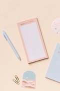 Extra small notepads with a pink and blue cover, alongside a pen, paper clips, washi tape, and a glue stick, all arranged on a beige background.