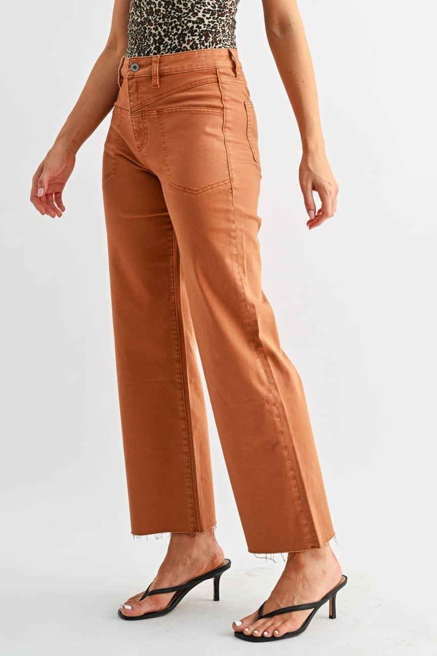 A woman modeling a sleeveless leopard-print halter top and rust-colored wide-leg cropped pants with black heeled sandals, photographed against a light gray studio background.