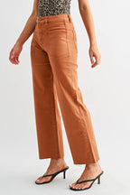 A woman modeling a sleeveless leopard-print halter top and rust-colored wide-leg cropped pants with black heeled sandals, photographed against a light gray studio background.